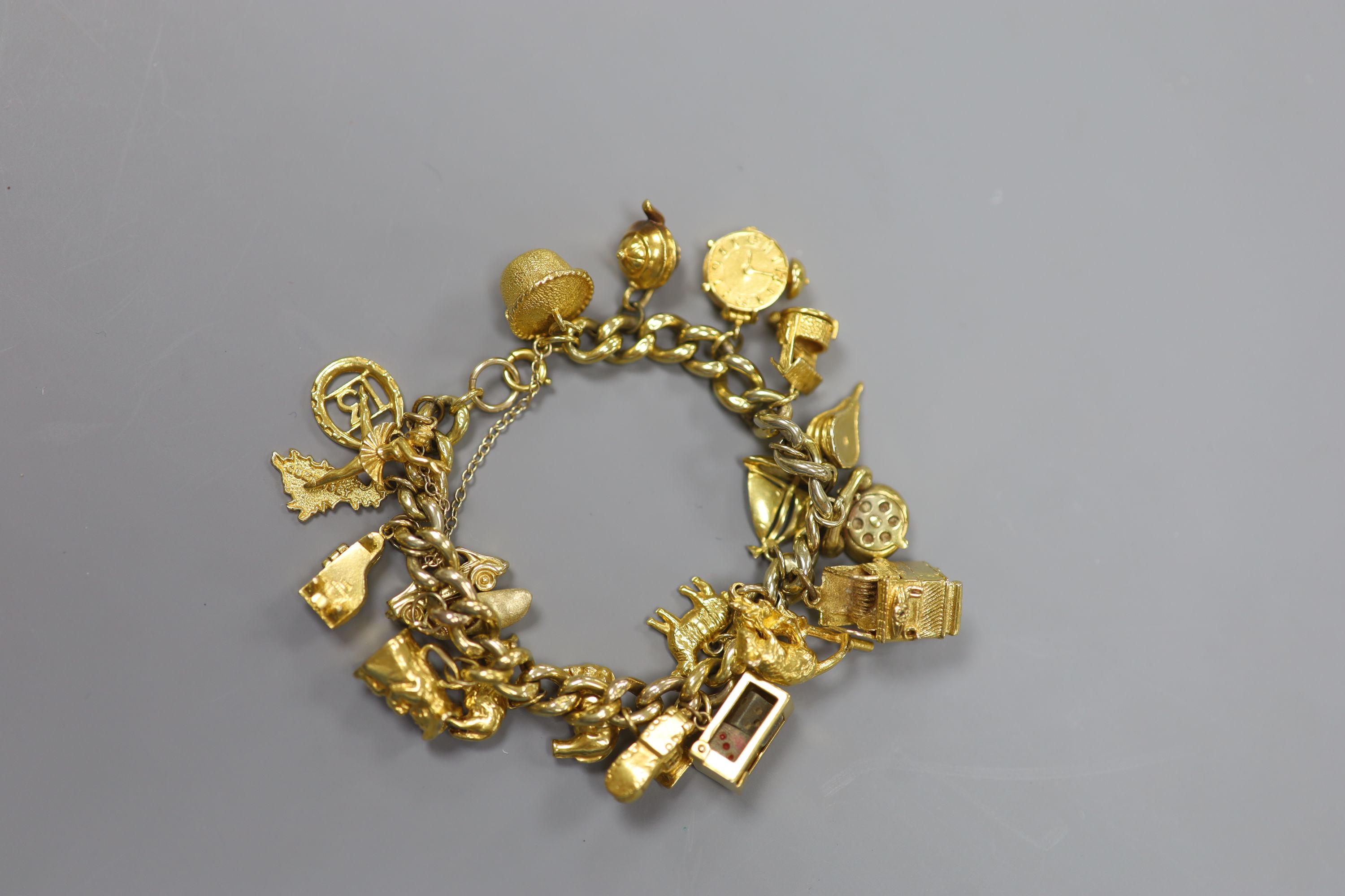 A 9ct curb link charm bracelet hung with twenty one assorted mainly 9ct gold charms